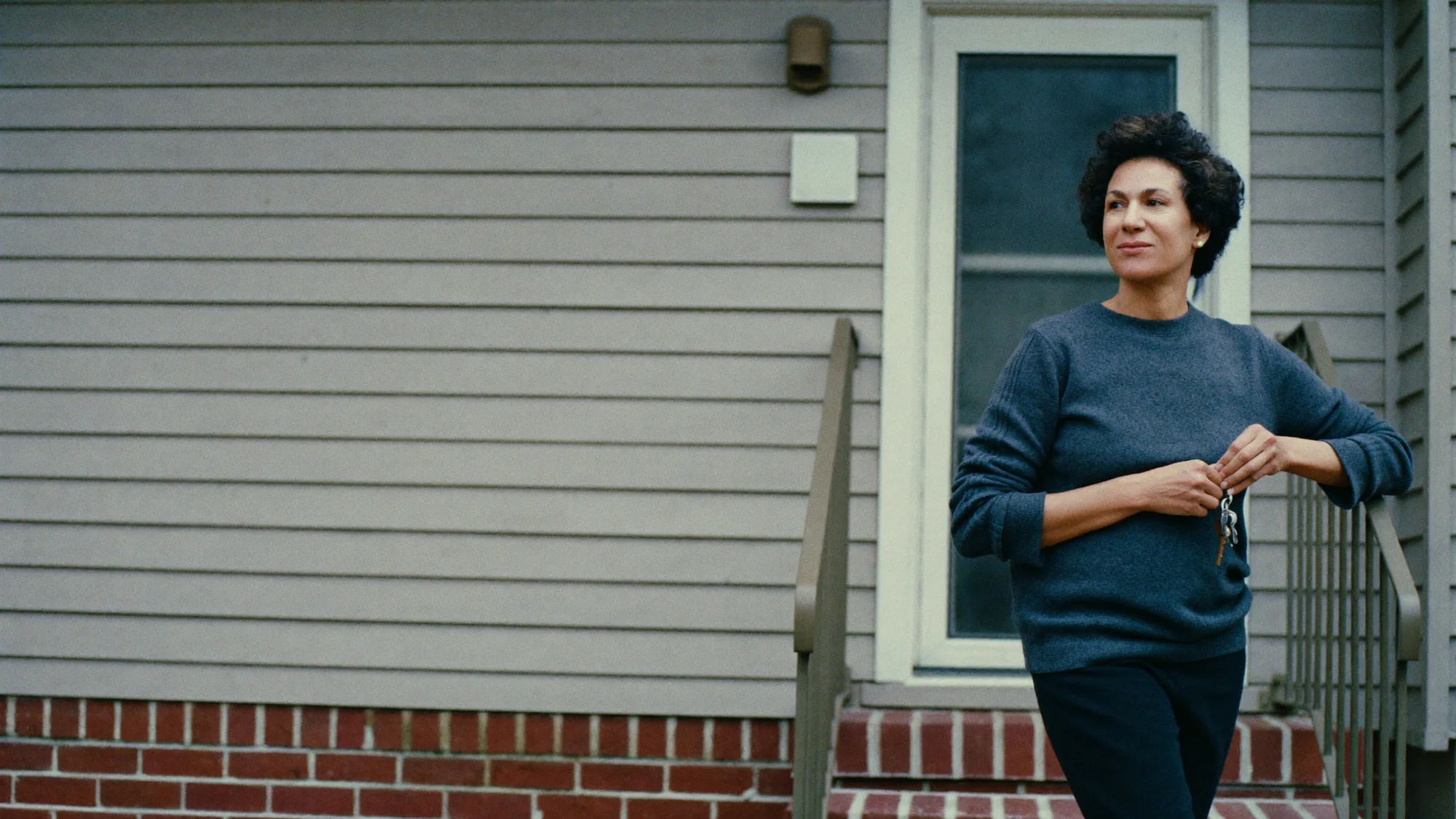 An independent landlord on the front steps of her rental property, keys in hand